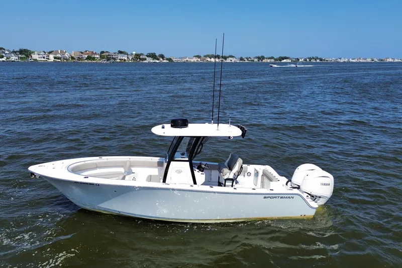 Slide: The Image of 2024 Sportsman Open 252 Center Console boat on calm water, coastal background. - 1