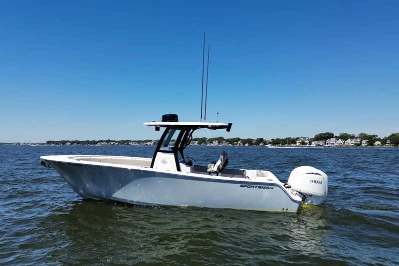 Slide: The Image of 2024 Sportsman Open 252 Center Console boat on calm water under clear blue sky. - 12