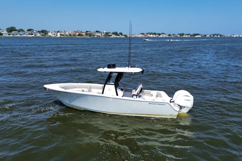 Slide: The Image of 2024 Sportsman Open 252 Center Console boat on calm water, coastal background. - 13