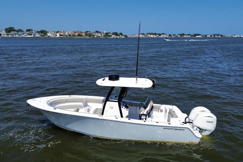 Slide: The Image of 2024 Sportsman Open 252 Center Console boat on calm water, coastal homes in background. - 14