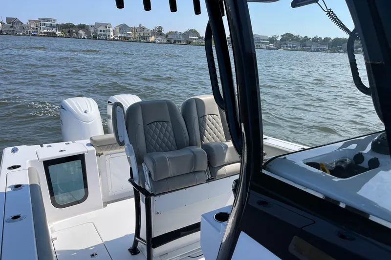 Slide: The Image of 2024 Sportsman Open 252 Center Console boat interior with dual seats on a calm water backdrop. - 18