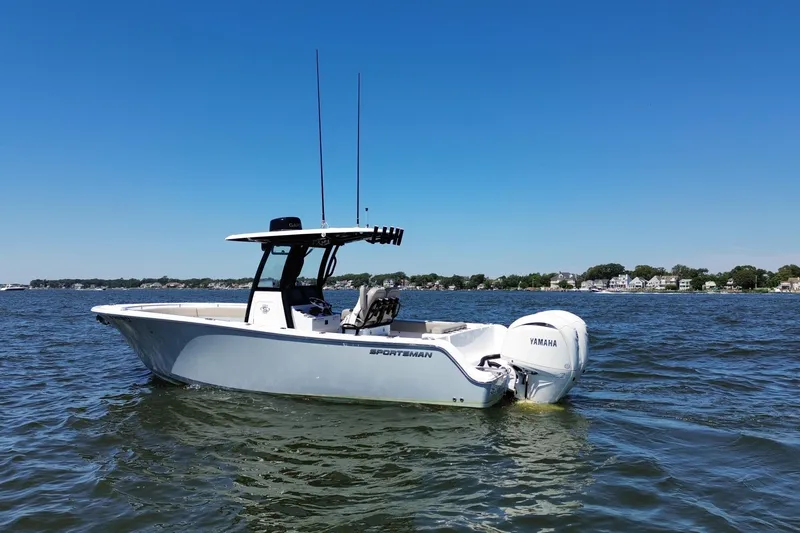 Slide: The Image of 2024 Sportsman Open 252 Center Console boat on calm water under clear blue sky. - 2