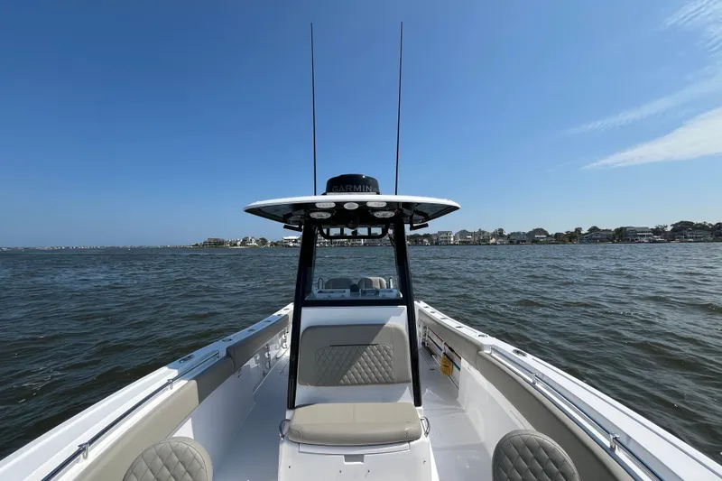 Slide: The Image of 2024 Sportsman Open 252 Center Console boat on calm waters under clear blue sky. - 21