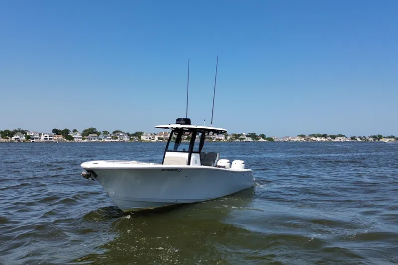 Slide: The Image of 2024 Sportsman Open 252 Center Console boat on calm water, clear sky background. - 7