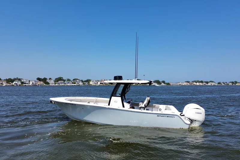 Slide: The Image of 2024 Sportsman Open 252 Center Console boat on calm water, coastal houses in background. - 8