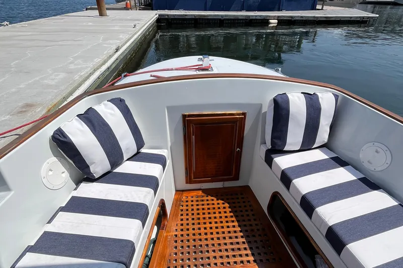 Slide: The Image of 2002 Duffy Electric 30 boat interior with striped cushions and wooden flooring at a dock. - 13