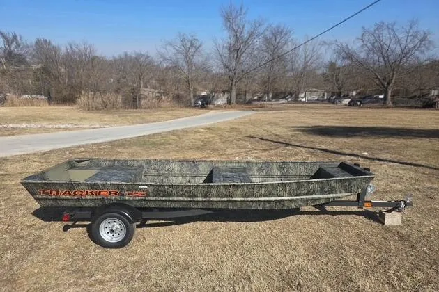 The Image of 2026 Tracker Grizzly 15 Jon boat on trailer in grassy area. - 0