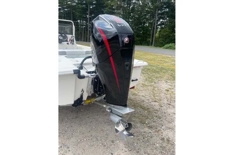 Slide: The Image of 2026 Mako 18 Pro Skiff with powerful outboard motor, parked on gravel near trees. - 6
