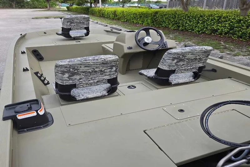 Slide: The Image of 2026 Tracker Grizzly 1754 SC boat interior with camo seats and steering console. - 3