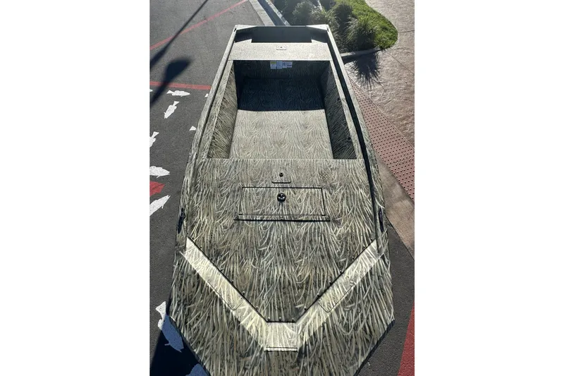 Slide: The Image of 2026 Tracker Grizzly 1648 Utility boat with camouflage design on pavement. - 2