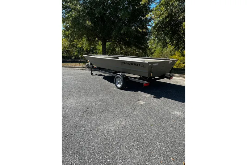 Slide: The Image of 2026 Tracker Grizzly 1648 Utility boat on trailer, parked outdoors under trees. - 3