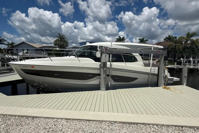 The Image of 2024 Beneteau Antares 11 docked under a cloudy sky, surrounded by palm trees. - 0