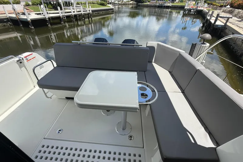 Slide: The Image of 2024 Beneteau Antares 11 boat interior with seating and table, docked by a calm waterway. - 12