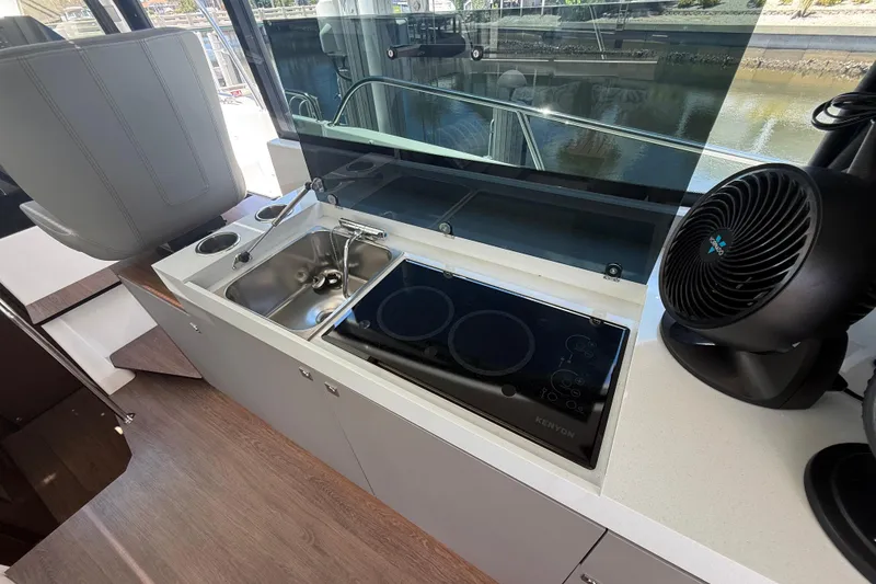 Slide: The Image of 2024 Beneteau Antares 11 kitchen area with sink, stove, and fan. - 14