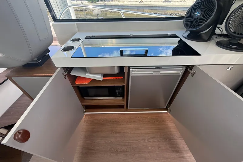 Slide: The Image of 2024 Beneteau Antares 11 interior kitchen with stove, sink, microwave, and refrigerator. - 15