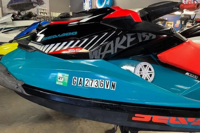 Slide: The Image of 2018 Sea-Doo Wake 155 jet ski in showroom, featuring vibrant blue and red design. - 4
