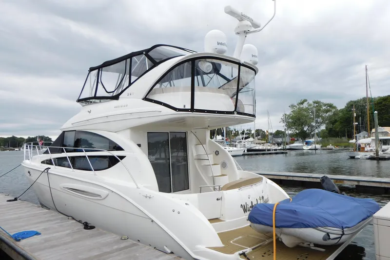 Slide: The Image of 2009 Meridian 391 Sedan yacht docked at marina, featuring sleek design and covered upper deck. - 2