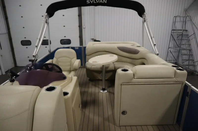 Slide: The Image of 2018 Sylvan 820 Mirage pontoon boat interior with beige seating and table. - 26