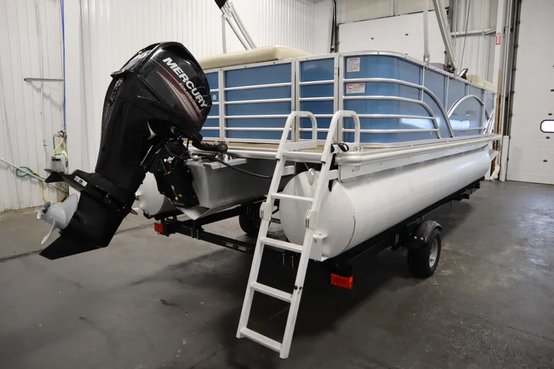 Slide: The Image of 2018 Sylvan 820 Mirage pontoon boat with Mercury outboard motor in a garage setting. - 34