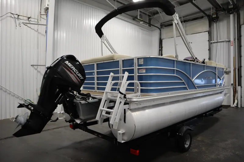 Slide: The Image of 2018 Sylvan 820 Mirage pontoon boat with Mercury outboard motor in a garage setting. - 5