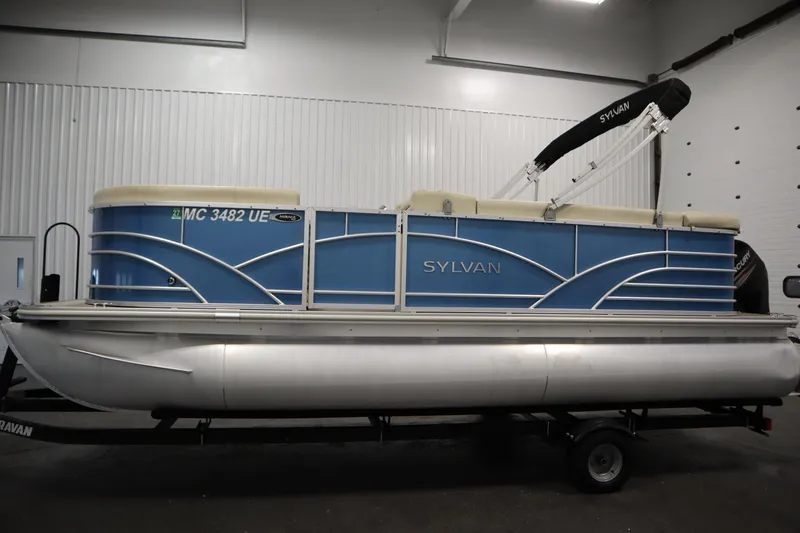 Slide: The Image of 2018 Sylvan 820 Mirage pontoon boat with blue exterior, displayed indoors. - 8