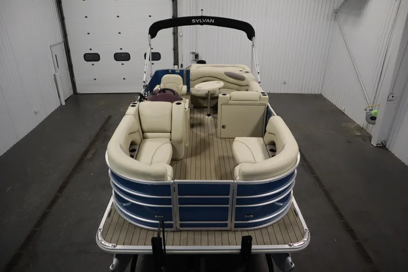 Slide: The Image of 2018 Sylvan 820 Mirage pontoon boat with beige seating in a garage setting. - 9