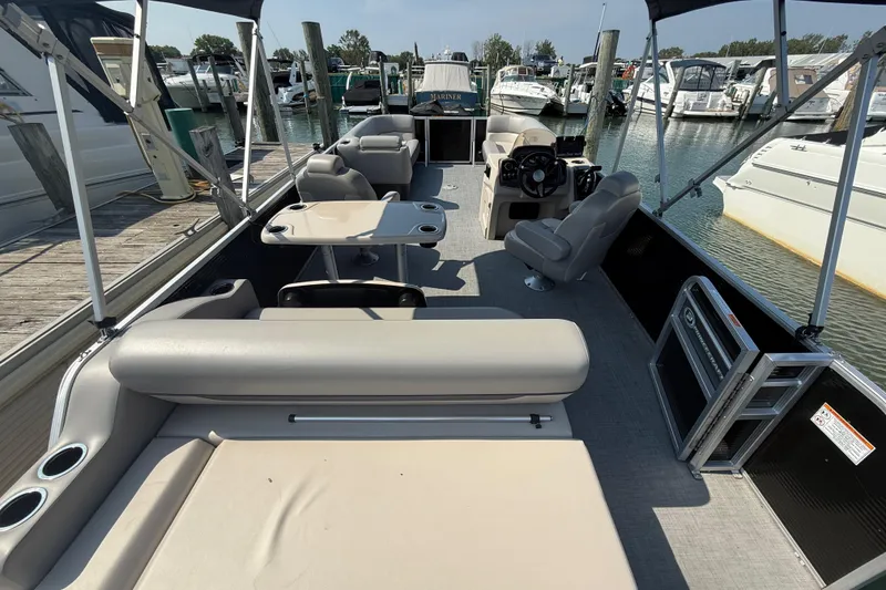 Slide: The Image of 2022 Princecraft Vectra 23 RL pontoon boat interior at marina, featuring seating and helm. - 6