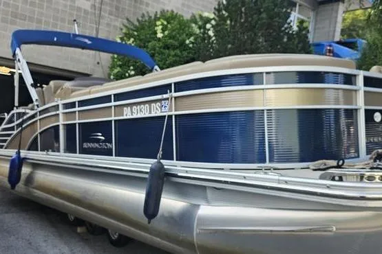 The Image of 2016 Bennington 2575 RCW pontoon boat with blue and beige exterior, docked outdoors. - 0