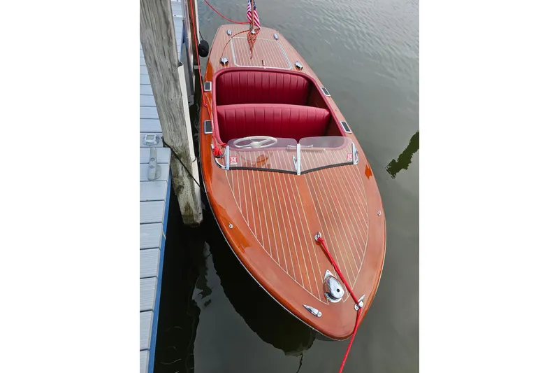 Slide: The Image of 1947 Chris Craft Barrel Back boat with wooden deck and red interior, docked at marina. - 11