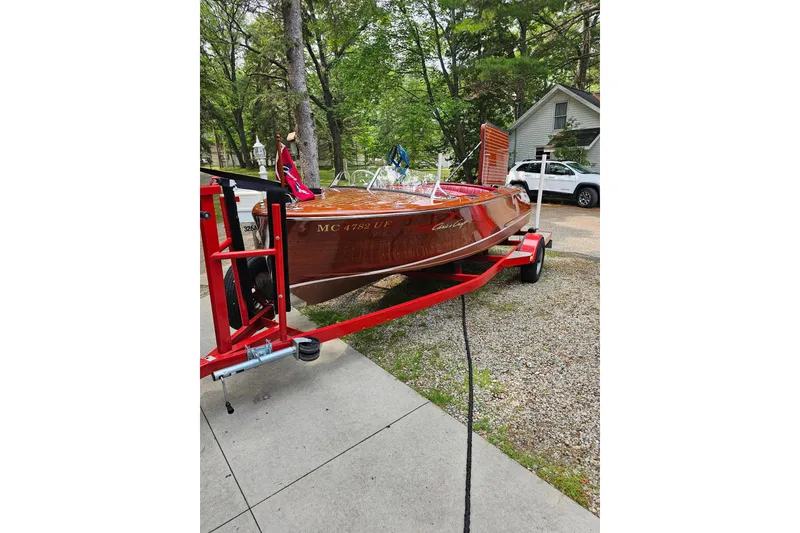 Slide: The Image of 1947 Chris Craft Barrel Back boat on red trailer, parked outdoors. - 14