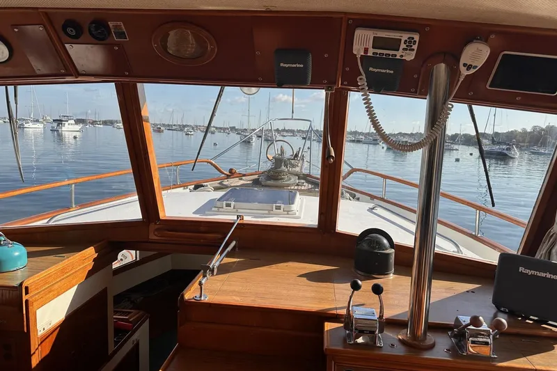 Slide: The Image of Interior view of 1984 Grand Banks 42 Classic yacht helm, overlooking a serene marina. - 10