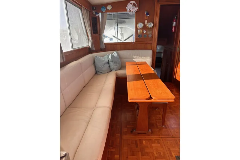 Slide: The Image of 1984 Grand Banks 42 Classic yacht interior with beige seating and wooden table. - 5