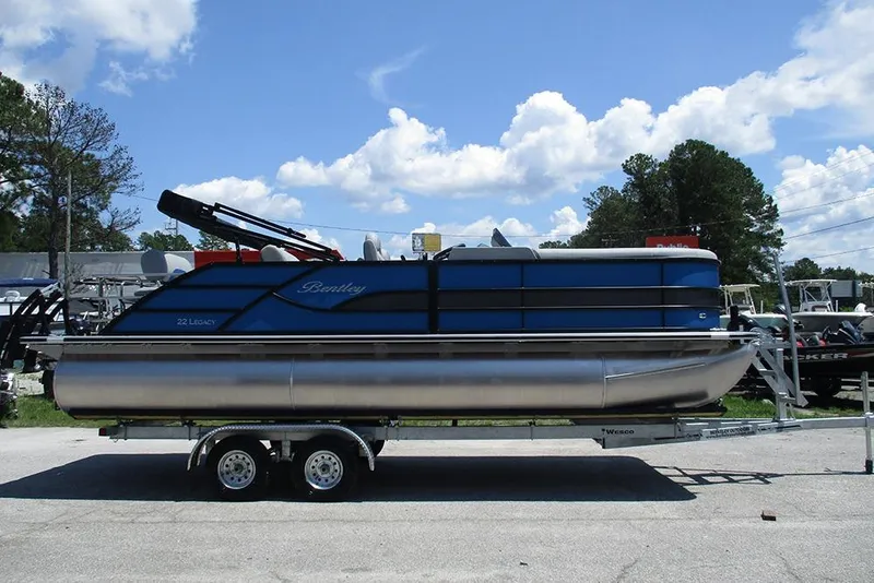 Slide: The Image of 2026 Bentley Pontoons Legacy 220 Quad Swingback on trailer, under a clear blue sky. - 6