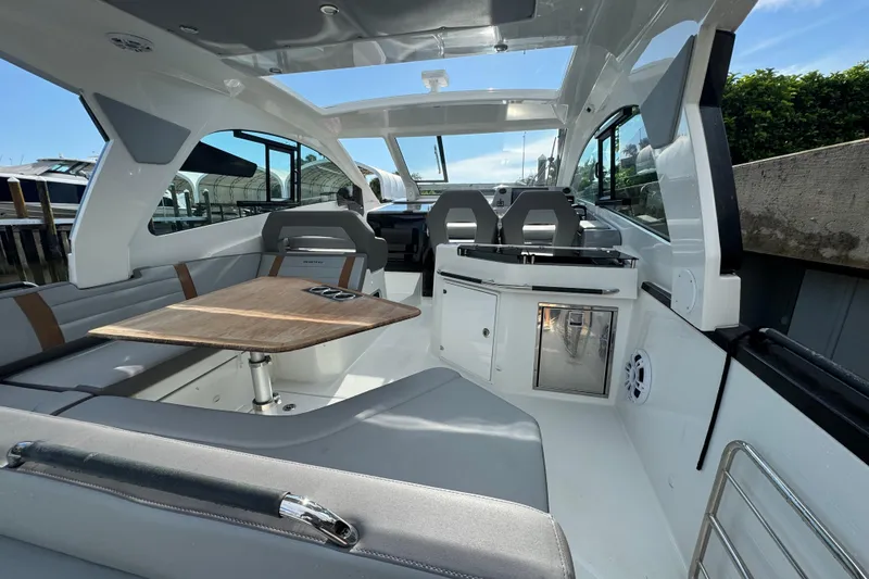 Slide: The Image of 2022 Beneteau Gran Turismo 32 interior with seating, table, and kitchenette under a sunny sky. - 10