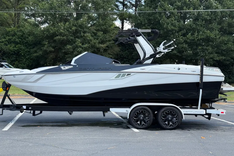 Slide: The Image of 2024 Centurion Fi23 boat on trailer, parked outdoors with trees in background. - 16