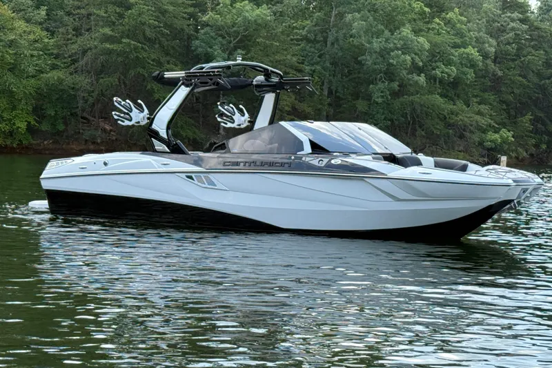Slide: The Image of 2024 Centurion Fi23 boat on a calm lake with lush green forest background. - 3