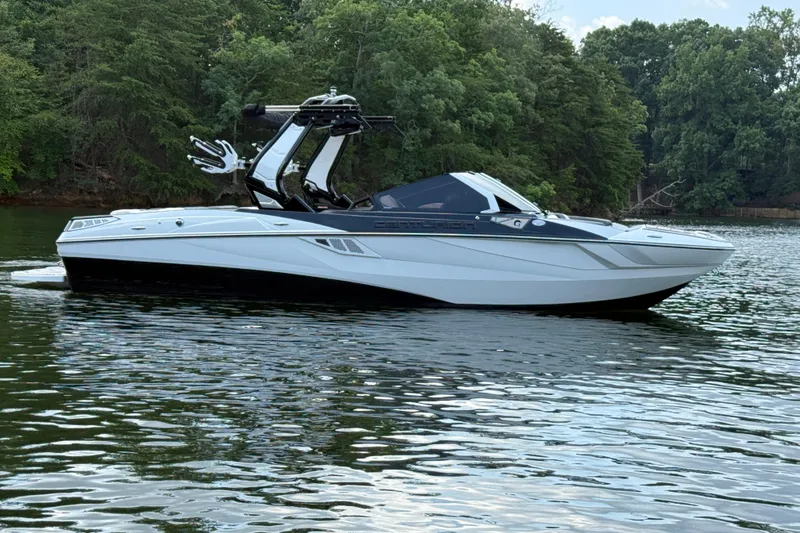 Slide: The Image of 2024 Centurion Fi23 boat on a calm lake with lush green trees. - 4