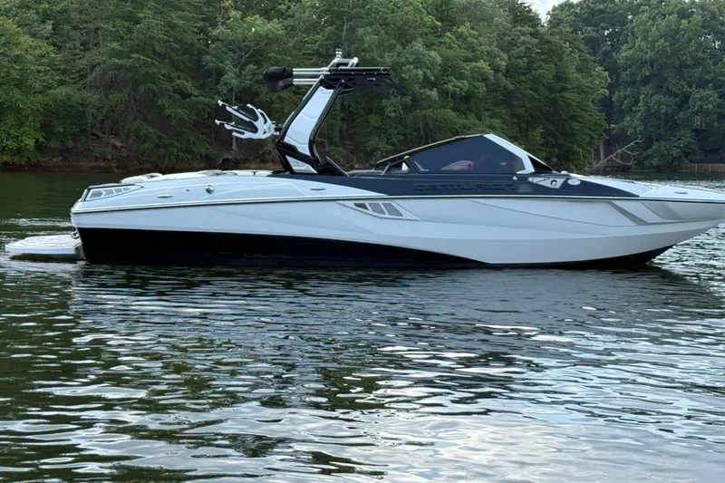 Slide: The Image of 2024 Centurion Fi23 boat on a calm lake with lush green trees in the background. - 5