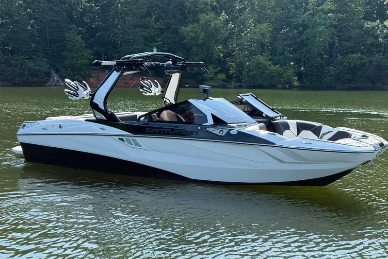 Slide: The Image of 2024 Centurion Fi23 boat on a calm lake, surrounded by lush greenery. - 6