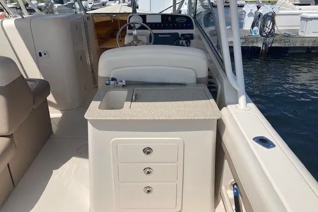 Slide: The Image of 2014 Grady-White Freedom 285 boat interior with helm, sink, and storage drawers. - 6