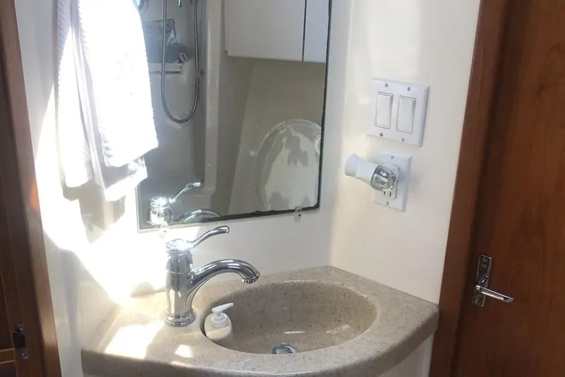 Slide: The Image of Bathroom sink area in a 1998 Tiara Yachts 3700 Open, featuring a mirror and faucet. - 25