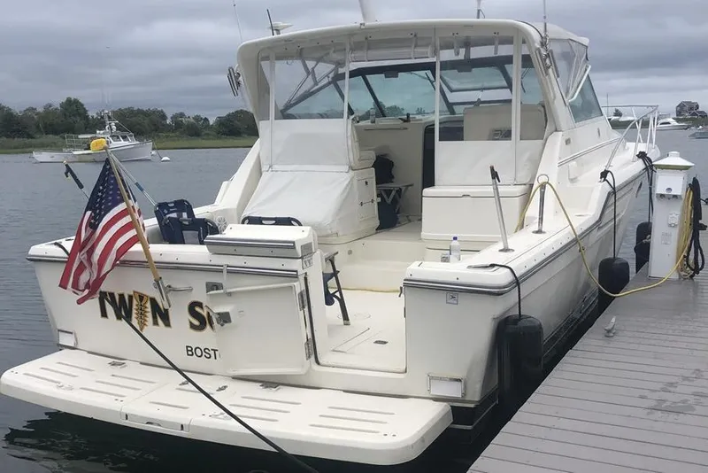 Slide: The Image of 1998 Tiara Yachts 3700 Open docked, featuring spacious deck and American flag. - 3