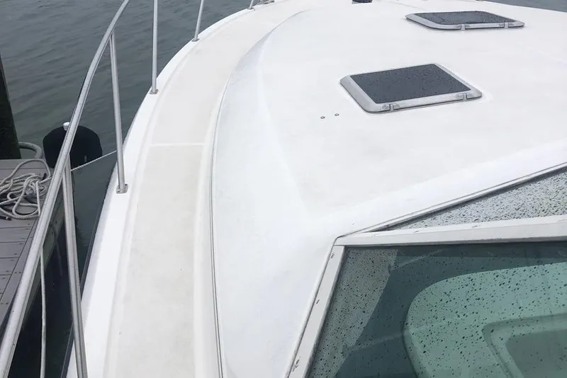 Slide: The Image of 1998 Tiara Yachts 3700 Open boat deck with railing and hatches, docked by water. - 35