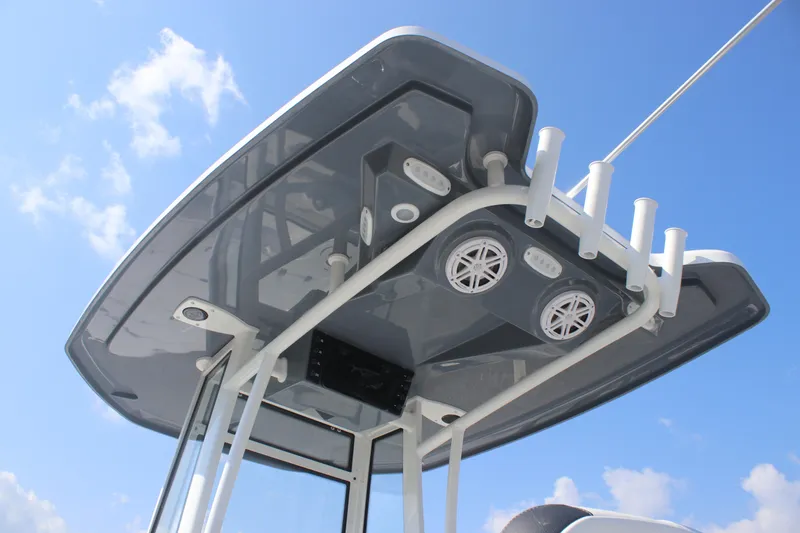 Slide: The Image of 2026 Tidewater 2110 Bay Max boat T-top with rod holders and speakers against blue sky. - 14