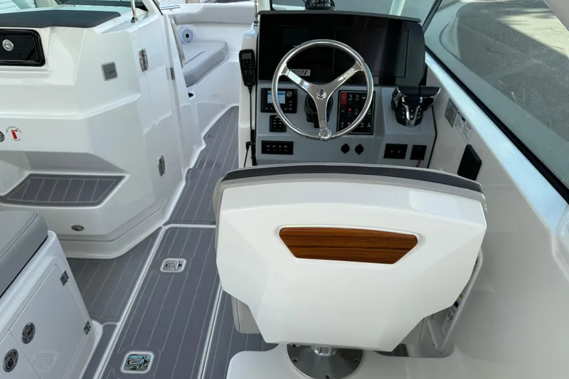 Slide: The Image of 2024 Pursuit DC 266 Dual Console boat interior with steering wheel and control panel. - 10