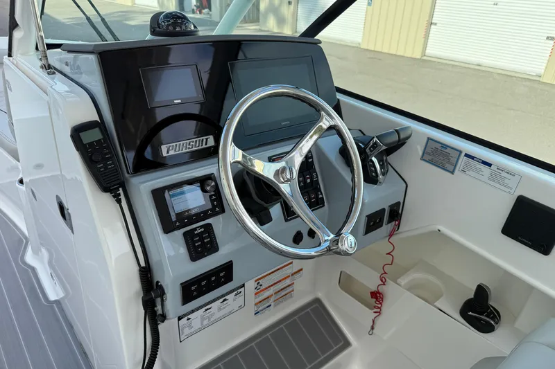 Slide: The Image of 2024 Pursuit DC 266 Dual Console boat dashboard with steering wheel and navigation controls. - 11