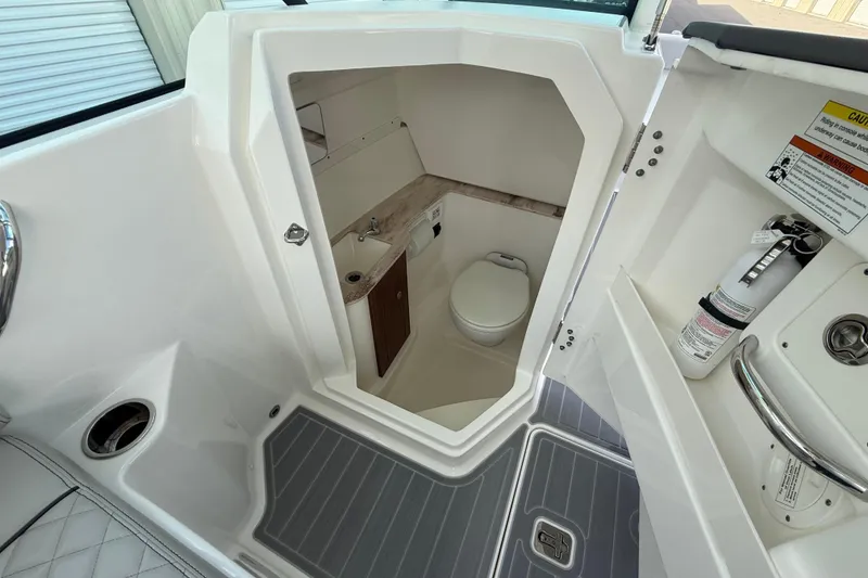 Slide: The Image of 2024 Pursuit DC 266 Dual Console boat interior with compact bathroom and safety equipment. - 18