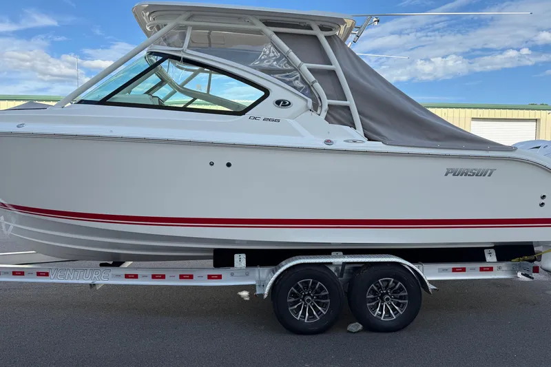 Slide: The Image of 2024 Pursuit DC 266 Dual Console boat on trailer, side view, clear sky background. - 2