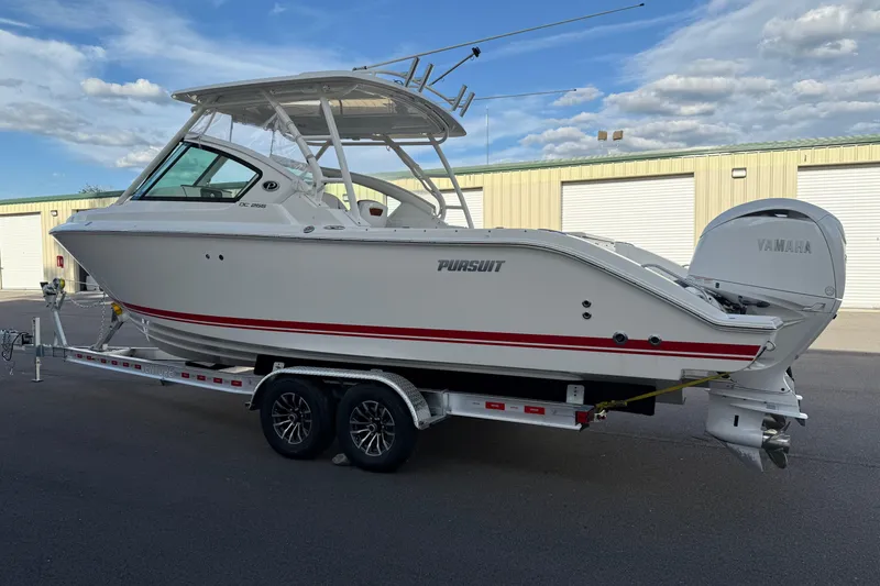 Slide: The Image of 2024 Pursuit DC 266 Dual Console boat on trailer, parked outdoors. - 23