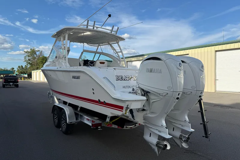 Slide: The Image of 2024 Pursuit DC 266 Dual Console boat with twin Yamaha engines on a trailer. - 24